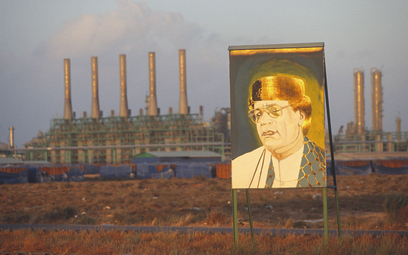 Pozłacany portret libijskiego przywódcy Muammara Kaddafiego (1942–2011) na tle rafinerii ropy naftow