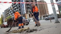 Pracownicy komunalni sprzątają teren w miejscu ataku rosyjskiego drona w trakcie rosyjskiego ataku n
