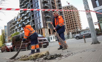 Pracownicy komunalni sprzątają teren w miejscu ataku rosyjskiego drona w trakcie rosyjskiego ataku n