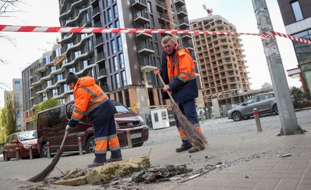 Pracownicy komunalni sprzątają teren w miejscu ataku rosyjskiego drona w trakcie rosyjskiego ataku n