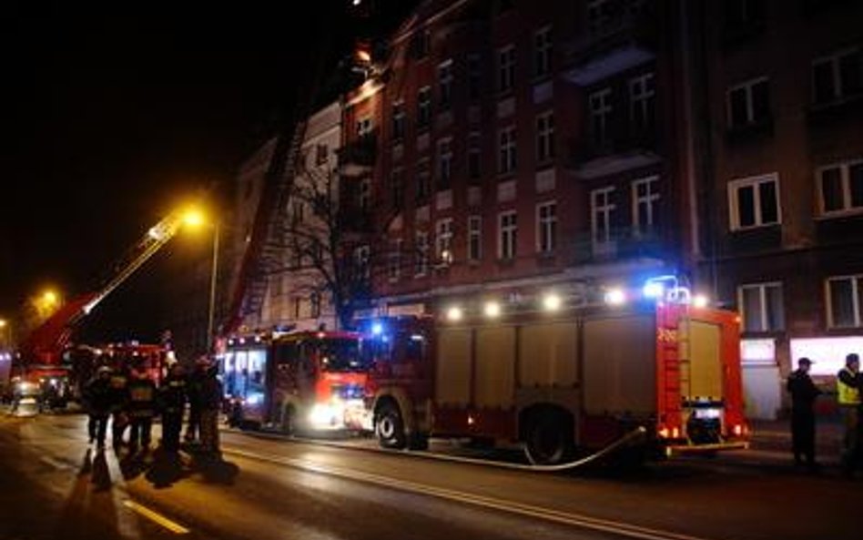 Straż pożarna i inne służby na miejscu pożaru, jaki wybuchł w kamienicy w Kaliszu późnym wieczorem