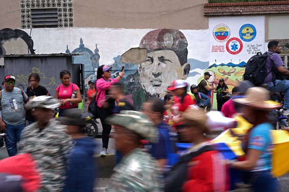 Przechodnie stojący w pobliżu muralu przedstawiającego nieżyjącego prezydenta Wenezueli Hugo Cháveza