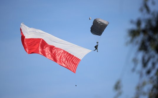 Skoczek spadochronowy z polską flagą podczas defilady wojskowej na warszawskiej Wisłostradzie, w ram