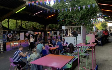 Warszawiacy relaksują się przy kolorowych stolikach, delektując się posiłkami i rozmowami,