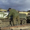 Rosyjski żołnierz umieszcza symbol "Z" na jednym z wozów bojowych