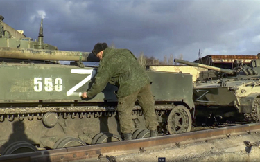 Rosyjski żołnierz umieszcza symbol "Z" na jednym z wozów bojowych