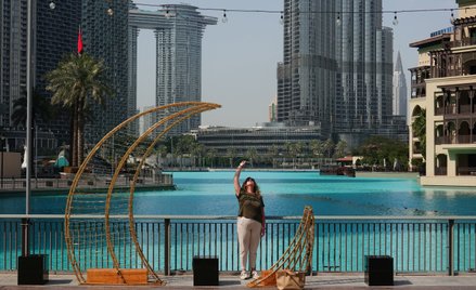 Turystka spoglądająca na niebo w pobliżu Burdż Chalifa w Dubaju. Wcześniej doszło do ataku Iranu, kt