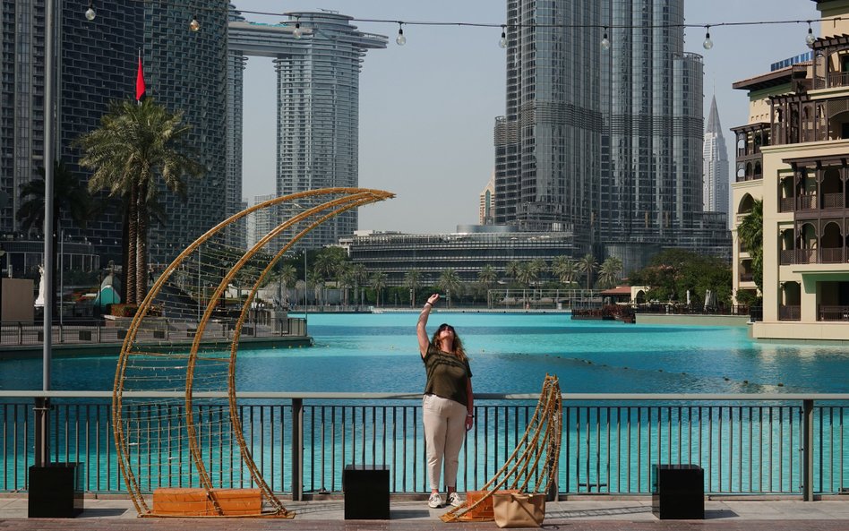 Turystka spoglądająca na niebo w pobliżu Burdż Chalifa w Dubaju. Wcześniej doszło do ataku Iranu, kt