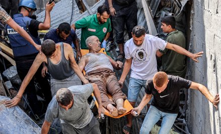 Ratownicy wydobywają spod gruzów osobę ranną w izraelskim ataku