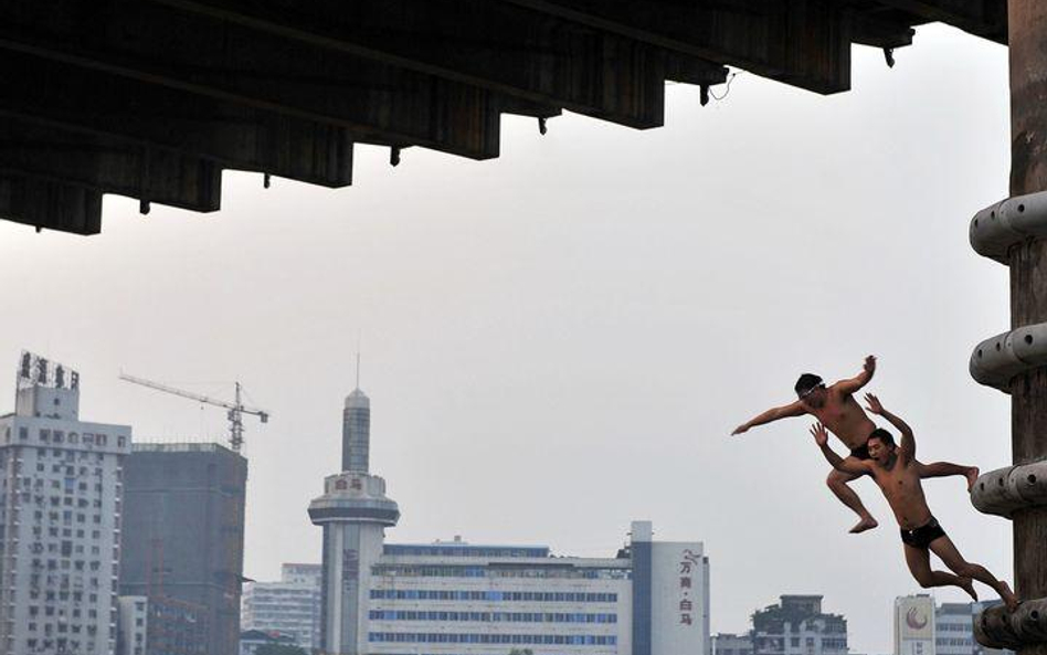 Chiny, Wuhan. Mężczyźni dla ochrony przed upałem skaczą z mostu do rzeki Jangcy