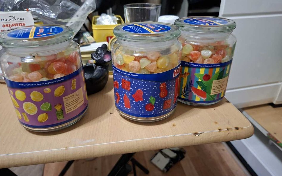 W komodzie oraz przy oknie znajdowały się szklane słoiki i plastikowe pudełka wypełnione kolorowymi 