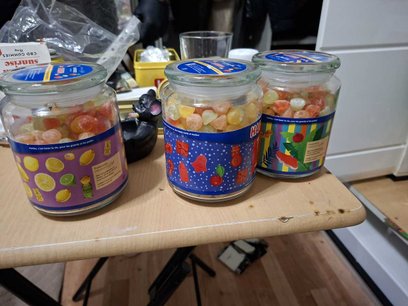 W komodzie oraz przy oknie znajdowały się szklane słoiki i plastikowe pudełka wypełnione kolorowymi 